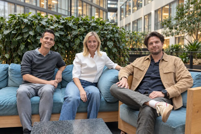 Sashas tre grundare sitter tillsammans i en blå soffa.